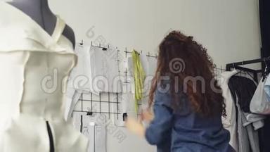 年轻的服装设计师正在灯光车间的墙面上看草图和<strong>挂画</strong>.. 大型收藏品